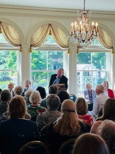 Former Wisconsin Governor Marty Schreiber talking at a podium in front of a crowd at the Governor's residence