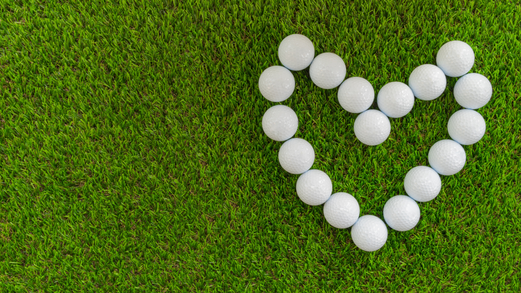 Green grassy background with golf balls in the shape of a heart