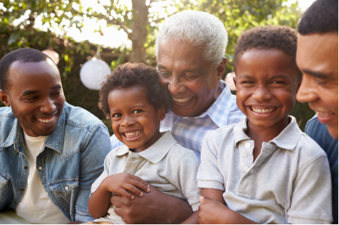 Multi-generational African American family hugging and laughing together