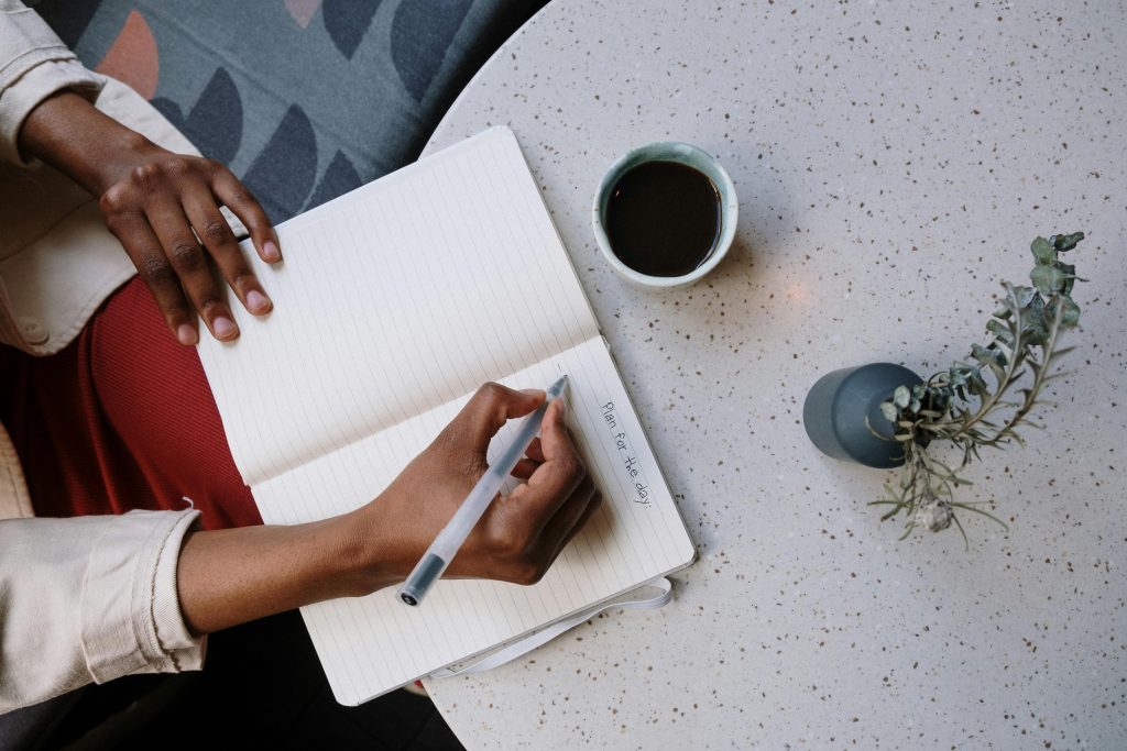 Person writing in a journal with a cup of coffee.