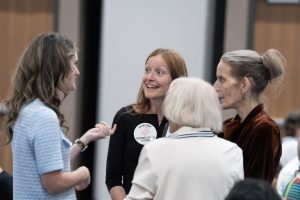 Four people stand together talking and laughing.